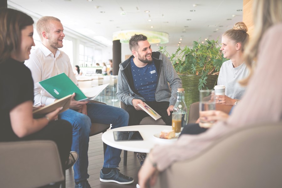Lächelnde Menschen sitzen um einen Tisch in einem Büro.