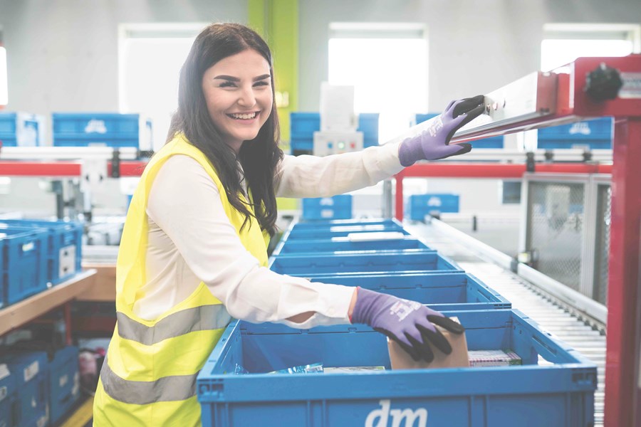 Junge Frau schlichtet Produkte in eine Transportkiste.